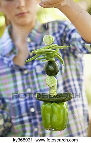 Stock Image - Girl holding a stack of tied up vegetables. Fotosearch