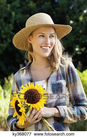 Happy young woman holding sunflowers in a field View Large Photo Image Stock Photo - Happy young woman holding sunflowers in a field. Fotosearch