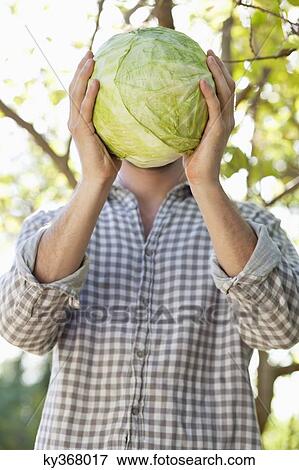 Man holding a cabbage in front of his face View Large Photo Image Stock Photo - Man holding a cabbage in front of his face. Fotosearch