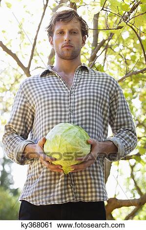 Stock Image - Portrait of a man holding a cabbage. Fotosearch