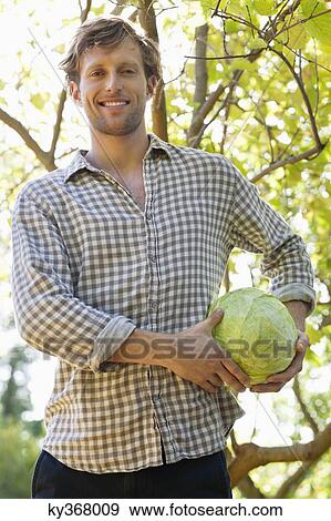 Portrait of a man holding a cabbage View Large Photo Image Stock Photo - Portrait of a man holding a cabbage. Fotosearch