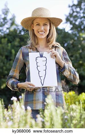 Portrait of a young woman showing carrot painting in a field View Large Photo Image Stock Photograph - Portrait of a young woman showing carrot painting in a field. Fotosearch