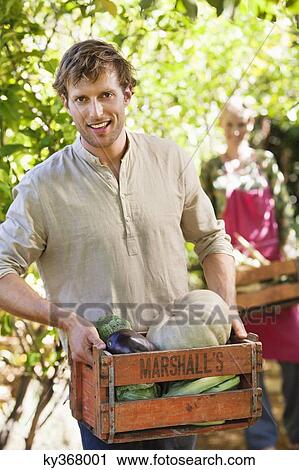 Smiling man holding a crate of vegetables View Large Photo Image Stock Image - Smiling man holding a crate of vegetables. Fotosearch
