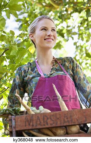 Smiling woman holding a crate of radish View Large Photo Image Stock Photo - Smiling woman holding a crate of radish. Fotosearch