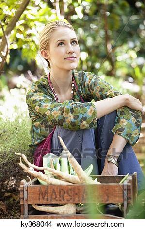 Woman sitting near a crate of radish and day dreaming View Large Photo Image Picture - Woman sitting near a crate of radish and day dreaming. Fotosearch