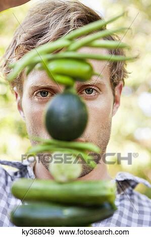 Young man holding vegetables View Large Photo Image Stock Photo - Young man holding vegetables. Fotosearch
