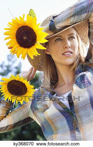 Stock Image - Young woman holding sunflowers. Fotosearch