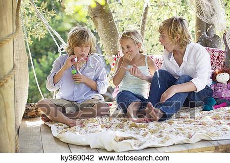 Children blowing bubble wand in tree house View Large Photo Image Stock Image - Children blowing bubble wand in tree house. Fotosearch