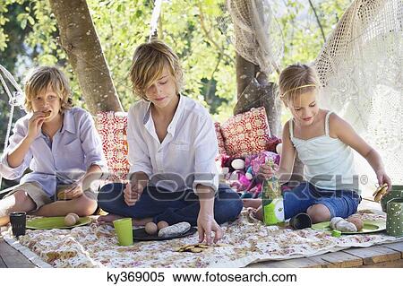 Stock Photography - Children eating food in tree house. Fotosearch