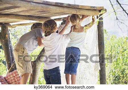 Children hanging curtain in tree house View Large Photo Image Picture - Children hanging curtain in tree house. Fotosearch