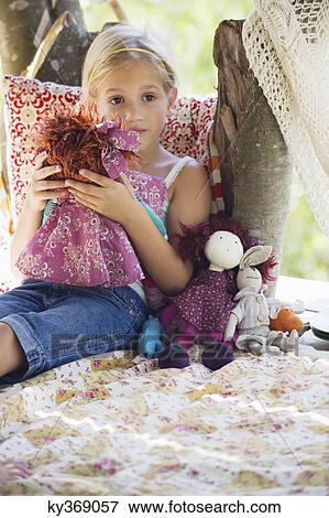 Contemplative little girl holding toys in tree house View Large Photo Image Stock Photo - Contemplative little girl holding toys in tree house. Fotosearch