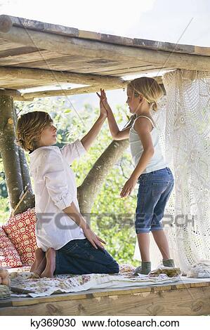 Happy siblings high fiving in tree house View Large Photo Image Stock Image - Happy siblings high fiving in tree house. Fotosearch