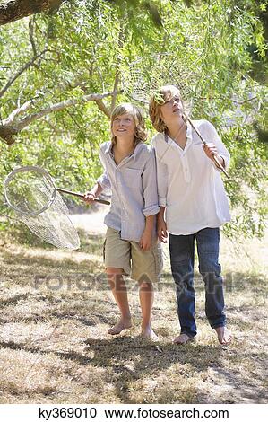 Little boys looking away in forest with net in hand View Large Photo Image Stock Image - Little boys looking away in forest with net in hand. Fotosearch