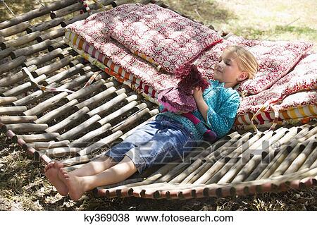 Little girl playing with toy while lying in hammock View Large Photo Image Stock Photo - Little girl playing with toy while lying in hammock. Fotosearch