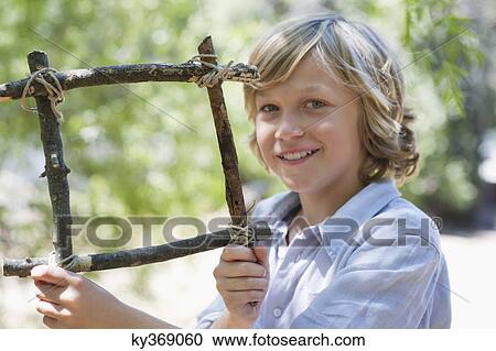 Portrait of a cute little boy holding frame of driftwood outdoors View Large Photo Image Stock Image - Portrait of a cute little boy holding frame of driftwood outdoors. Fotosearch