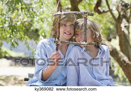 Portrait of children looking through frame of driftwood outdoors View Large Photo Image Stock Image - Portrait of children looking through frame of driftwood outdoors. Fotosearch