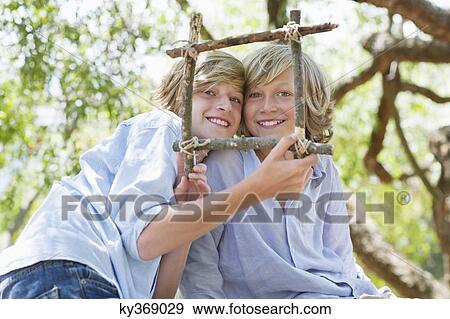 Portrait of children looking through frame of driftwood outdoors View Large Photo Image Stock Photo - Portrait of children looking through frame of driftwood outdoors. Fotosearch