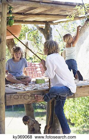 Rear view of a boy grasping rope to reach tree house View Large Photo Image Stock Photo - Rear view of a boy grasping rope to reach tree house. Fotosearch