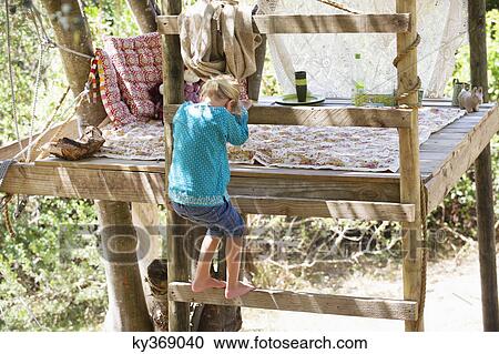 Stock Image - Rear view of a little girl getting down from the tree house. Fotosearch