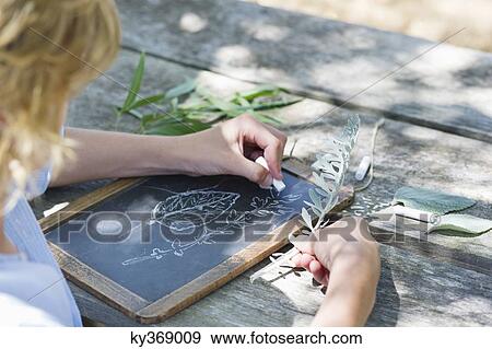 Side profile of a little boy making drawing of leaves on slate outdoors View Large Photo Image Stock Photo - Side profile of a little boy making drawing of leaves on slate outdoors. Fotosearch