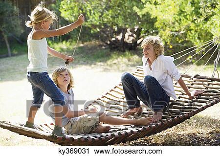 Stock Image - Smiling little siblings playing in hammock. Fotosearch