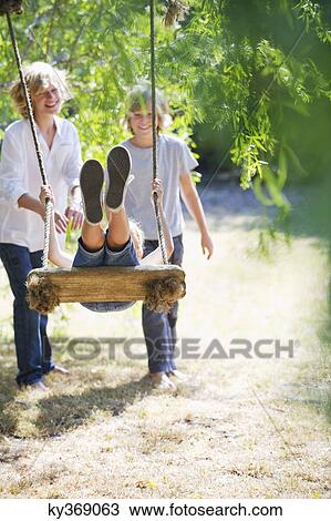 Smiling little siblings playing in tree swing View Large Photo Image Stock Image - Smiling little siblings playing in tree swing. Fotosearch