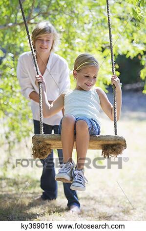 Stock Photograph - Smiling little siblings playing in tree swing. Fotosearch