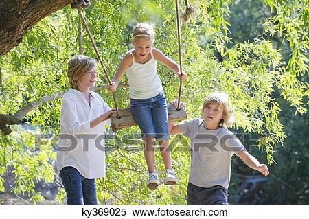 Smiling little siblings playing in tree swing View Large Photo Image Stock Photography - Smiling little siblings playing in tree swing. Fotosearch