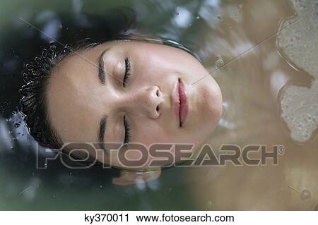 Beautiful young woman relaxing in a bathtub with her eyes closed View Large Photo Image Stock Image - Beautiful young woman relaxing in a bathtub with her eyes closed. Fotosearch