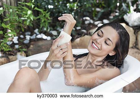 Stock Image - Beautiful young woman taking bubble bath. Fotosearch