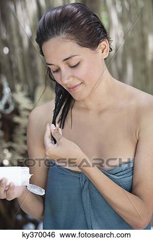 Beautiful young woman wrapped in towel and applying deep conditioner View Large Photo Image Stock Photograph - Beautiful young woman wrapped in towel and applying deep conditioner. Fotosearch