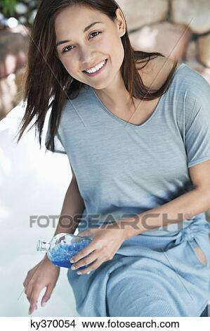 Portrait of a young woman pouring aromatherapy oil in bathtub View Large Photo Image Picture - Portrait of a young woman pouring aromatherapy oil in bathtub. Fotosearch