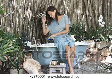 Young woman pouring aromatherapy oil in bathtub View Large Photo Image Stock Image - Young woman pouring aromatherapy oil in bathtub. Fotosearch