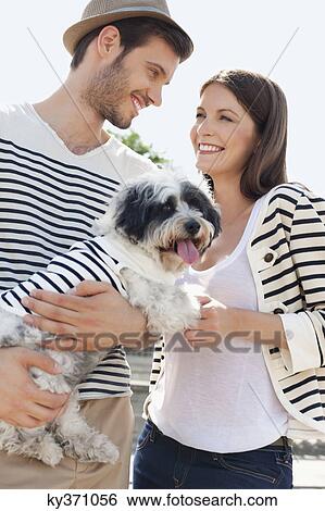 Stock Photograph - Couple carrying a puppy, Paris, Ile-de-France, France. Fotosearch