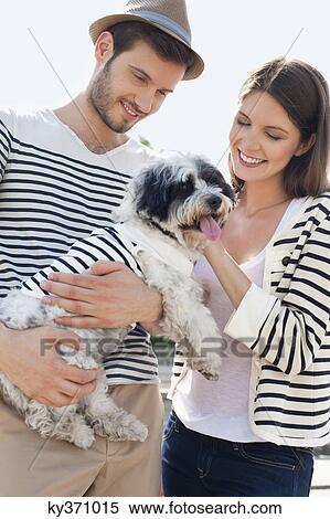 Stock Photography - Couple carrying a puppy, Paris, Ile-de-France, France. Fotosearch