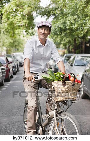 Stock Image - Man carrying vegetables on a bicycle, Paris, Ile-de-France, France. Fotosearch