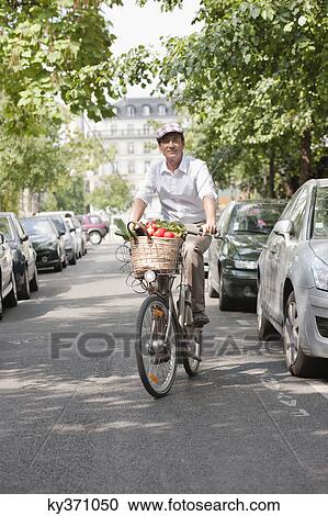 Stock Image - Man carrying vegetables on a bicycle, Paris, Ile-de-France, France. Fotosearch