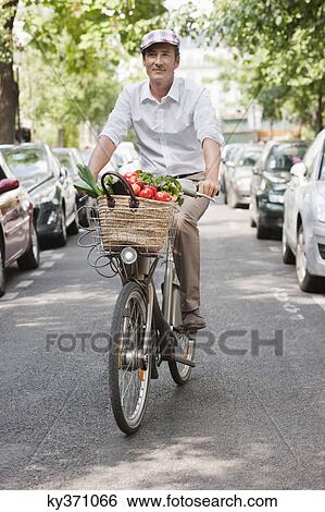 Stock Photograph - Man carrying vegetables on a bicycle, Paris, Ile-de-France, France. Fotosearch