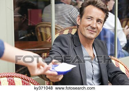 Stock Photo - Man receiving bill in a restaurant, Paris, Ile-de-France, France. Fotosearch