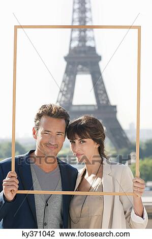 Stock Image - Portrait of a couple framing their dream vacation with Eiffel Tower, Paris, Ile-de-France, France. Fotosearch