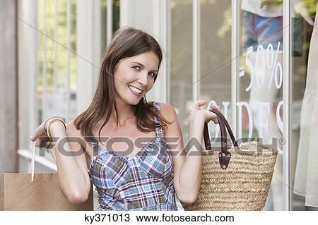 Stock Image - Woman holding shopping bag and smiling, Paris, Ile-de-France, France. Fotosearch