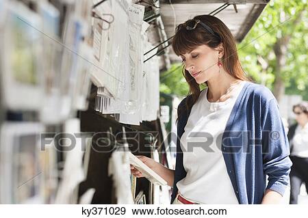 Stock Photo - Woman reading a book at a book stall, Paris, Ile-de-France, France. Fotosearch