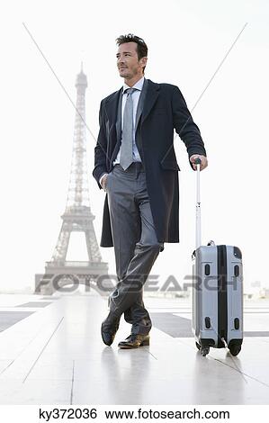 Businessman standing with luggage with the Eiffel Tower in the background, Paris, Ile-de-France, France View Large Photo Image Stock Photograph - Businessman standing with luggage with the Eiffel Tower in the background, Paris, Ile-de-France, France. Fotosearch