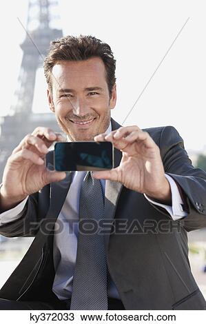 Businessman taking a picture of himself with the Eiffel Tower in the background, Paris, Ile-de-France, France View Large Photo Image Stock Image - Businessman taking a picture of himself with the Eiffel Tower in the background, Paris, Ile-de-France, France. Fotosearch