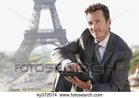 Businessman using a digital tablet with the Eiffel Tower in the background, Paris, Ile-de-France, France View Large Photo Image Picture - Businessman using a digital tablet with the Eiffel Tower in the background, Paris, Ile-de-France, France. Fotosearch
