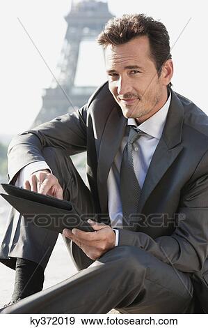 Stock Photo - Businessman using a digital tablet with the Eiffel Tower in the background, Paris, Ile-de-France, France. Fotosearch