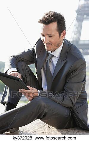 Businessman using a digital tablet with the Eiffel Tower in the background, Paris, Ile-de-France, France View Large Photo Image Stock Photo - Businessman using a digital tablet with the Eiffel Tower in the background, Paris, Ile-de-France, France. Fotosearch