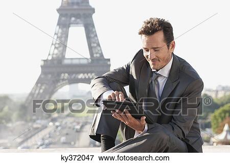 Stock Photo - Businessman using a digital tablet with the Eiffel Tower in the background, Paris, Ile-de-France, France. Fotosearch