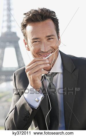 Stock Image - Businessman using a hands-free device with the Eiffel Tower in the background, Paris, Ile-de-France, France. Fotosearch