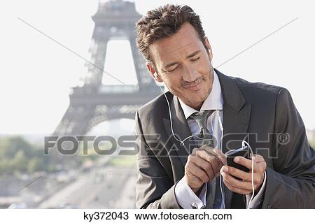 Stock Image - Businessman using a mobile phone with the Eiffel Tower in the background, Paris, Ile-de-France, France. Fotosearch